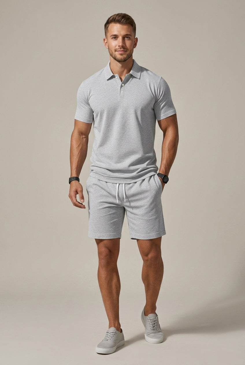 Man in a light grey Hugo polo shirt and matching drawstring shorts with side pockets.