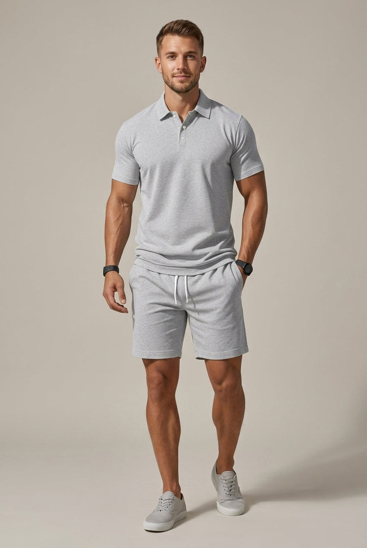 Man in a light grey Hugo polo shirt and matching drawstring shorts with side pockets.