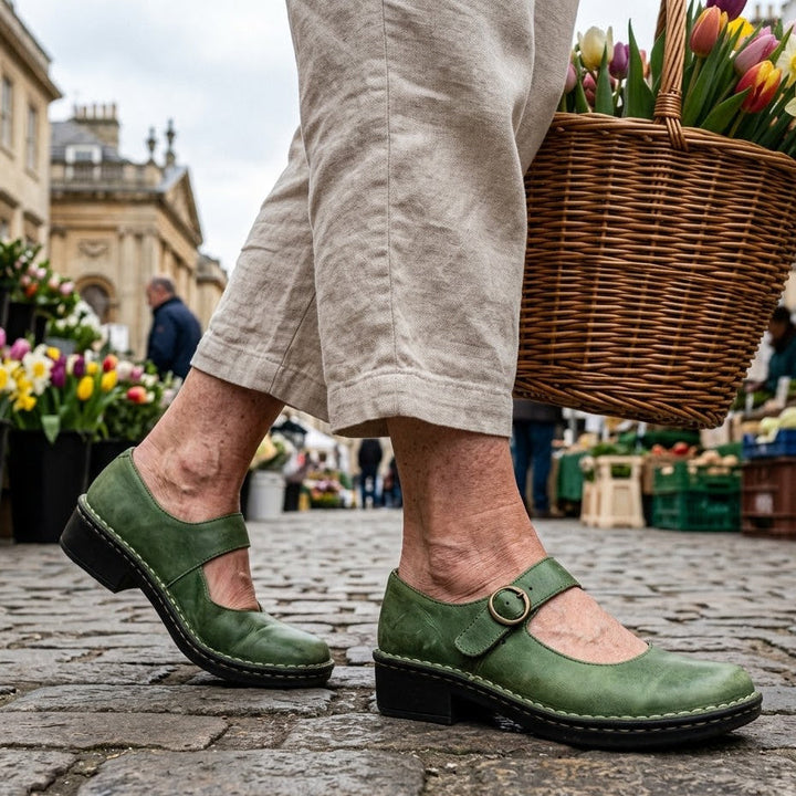 Green leather Isla Mary Jane shoes with a low heel worn on a cobblestone street.
