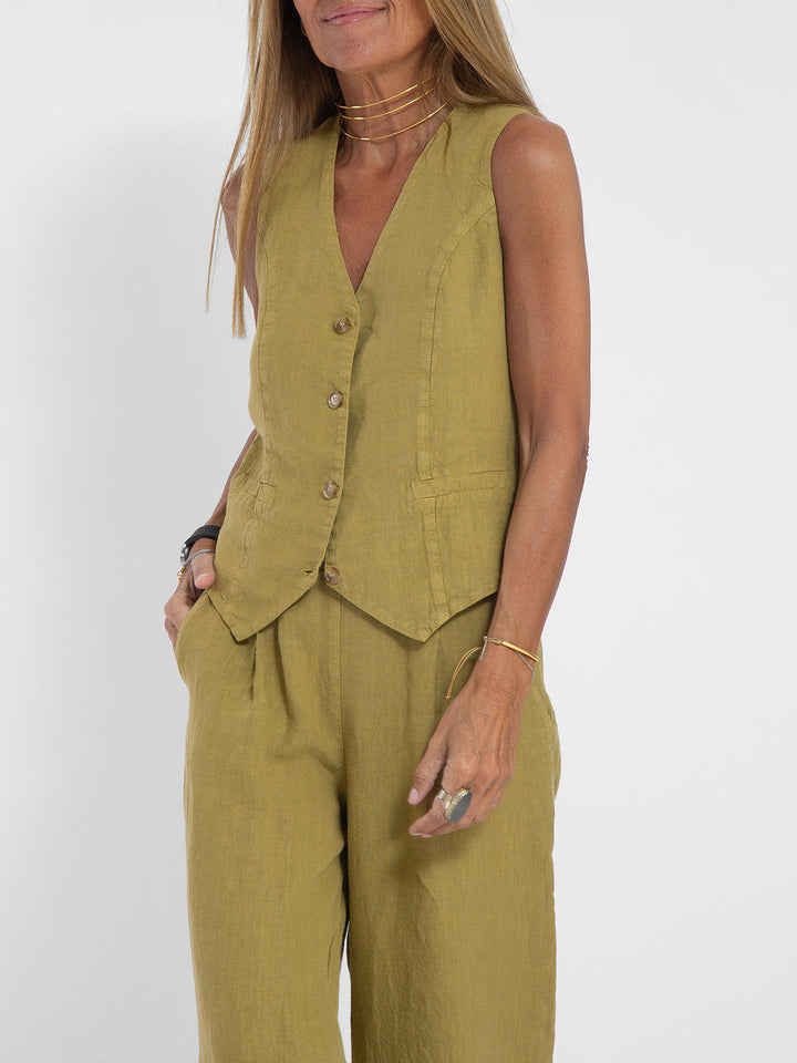 Woman wearing a Jhoana olive green linen vest and wide-leg pants set with gold jewelry.