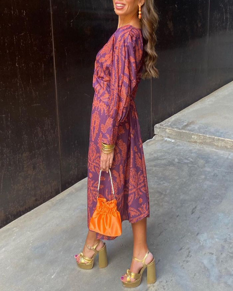 Woman in the Josephine purple and orange printed A-line maxi dress with gold heels.