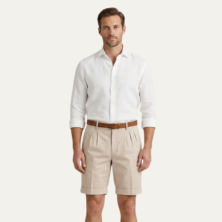 Men's Julian pleated chino shorts in light tan, with cuffed hems and a brown belt.