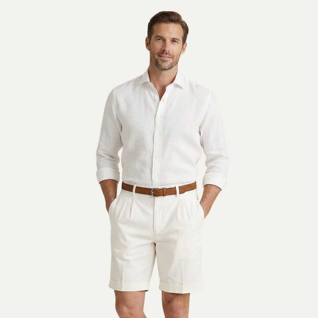 Man wearing white linen shirt, brown belt, and Julian men's pleated chino shorts with cuffed hems.