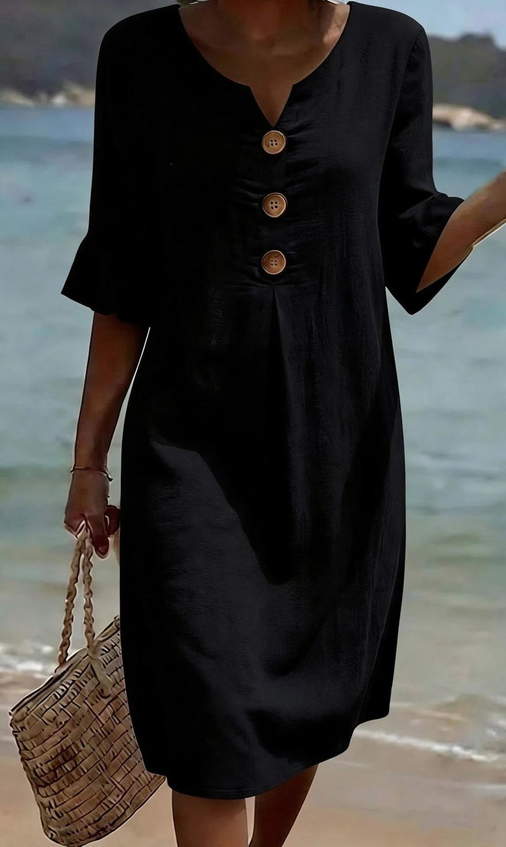 Black V-neck midi dress with ruffle sleeves and three front buttons, worn at the beach.
