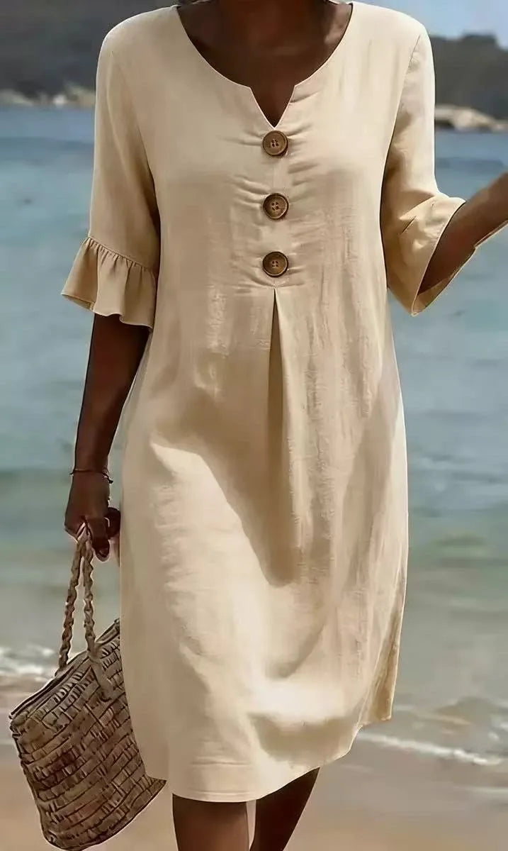 Beige linen V-neck midi dress with ruffle sleeves and three front buttons, worn on a beach.
