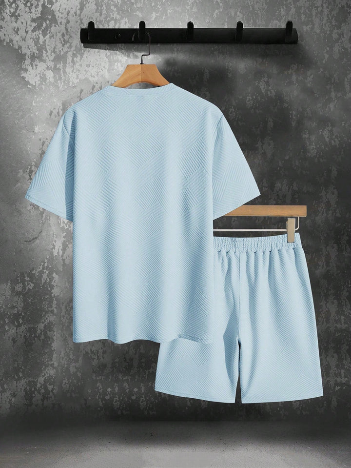 Light blue men's textured short sleeve t-shirt and matching drawstring shorts set, hanging against a gray wall.