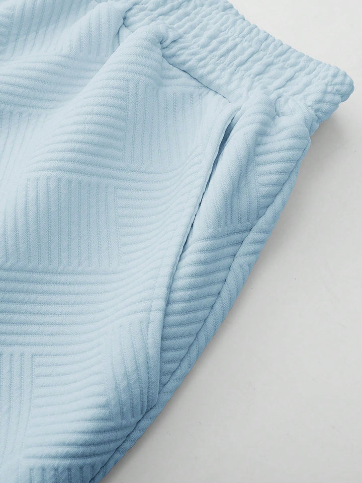 Close-up of light blue textured drawstring shorts with a subtle tonal pattern and side pocket.