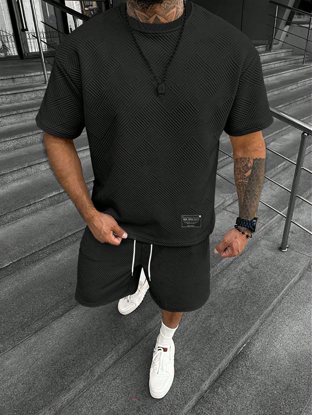 Men's black textured t-shirt and drawstring shorts set with a tonal pattern, worn by a model.