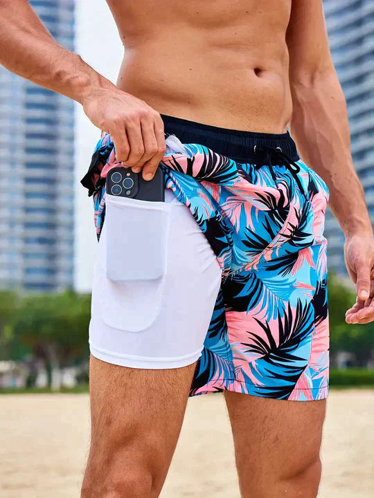 Men's Liam drawstring swim shorts with a vibrant blue and pink palm pattern, featuring a white inner lining with a phone pocket.