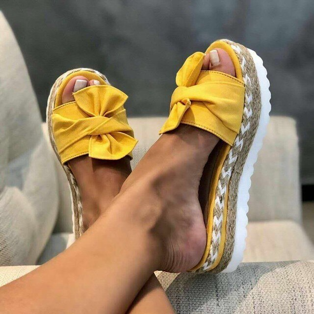 Women's yellow bow platform slide sandals with espadrille-style soles.