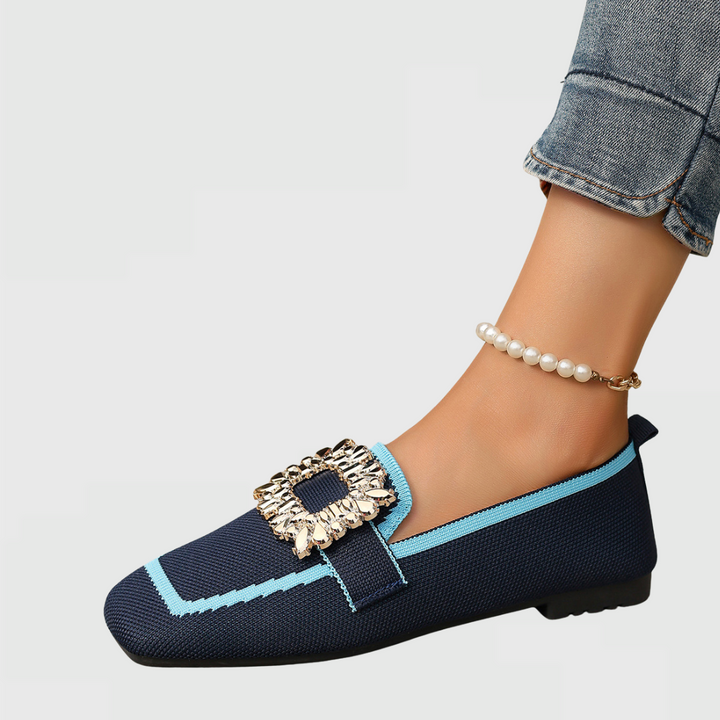 Black leather women's orthopedic loafers with a prominent gold statement buckle, side view.