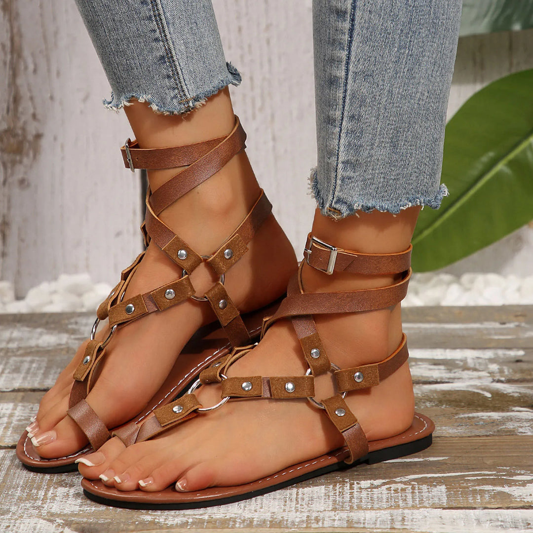 Brown leather Mia lace-up gladiator flat sandals with strappy buckle details, worn with denim jeans.