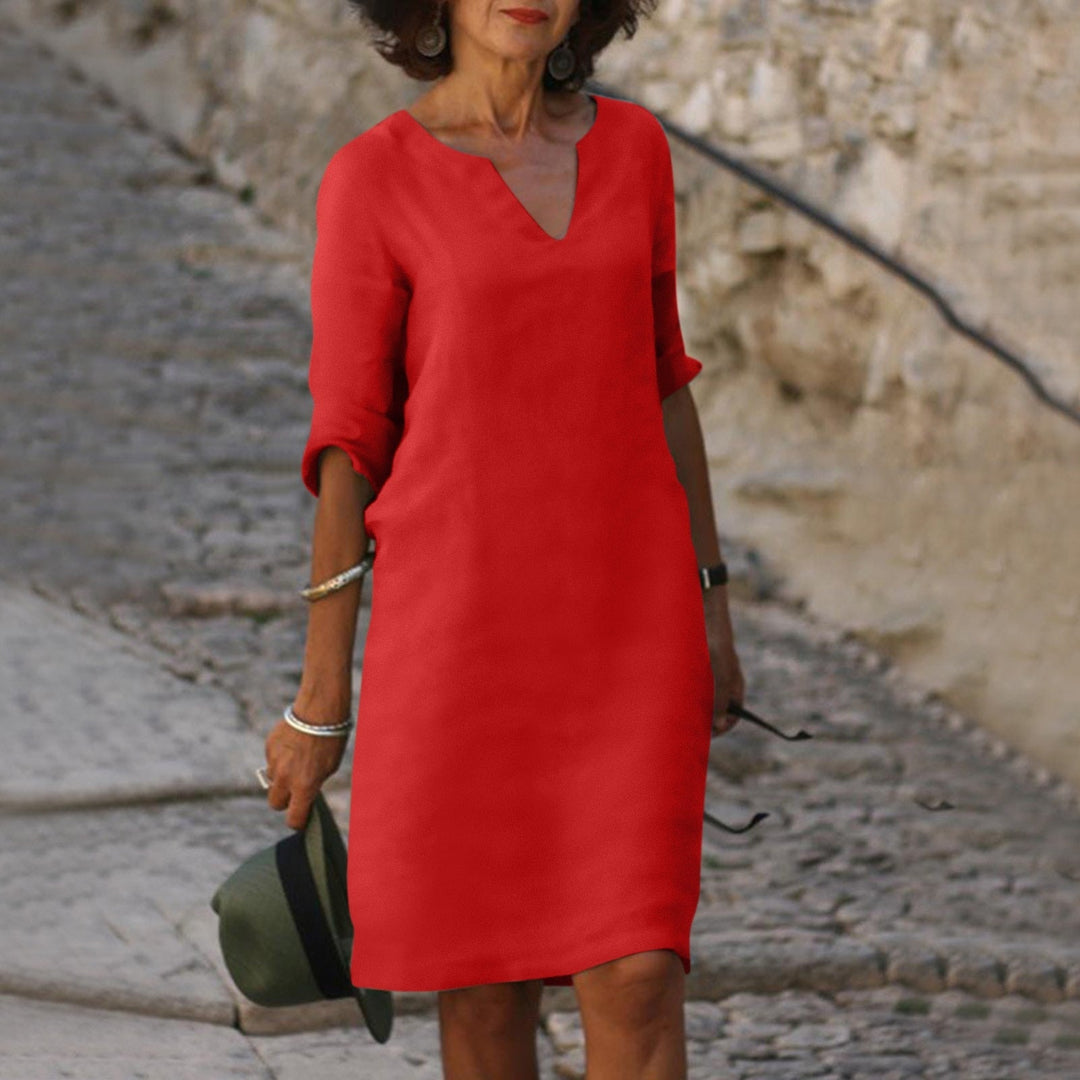 Woman in a vibrant red Mia summer dress with a V-neck and 3/4 sleeves, walking on stone steps.