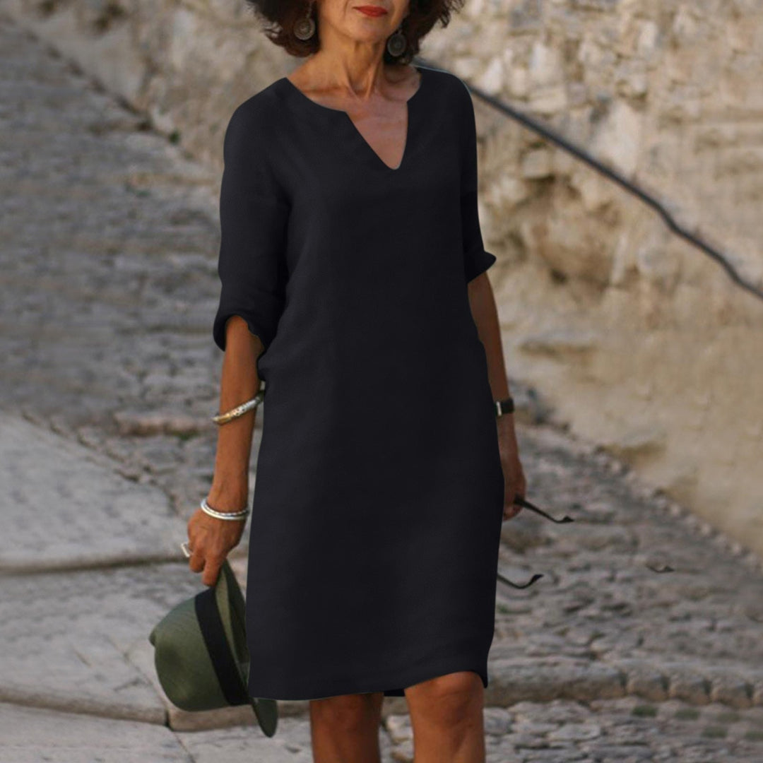 Woman in a black Mia summer dress with a flattering V-neck, 3/4 sleeves, and lightweight fabric.