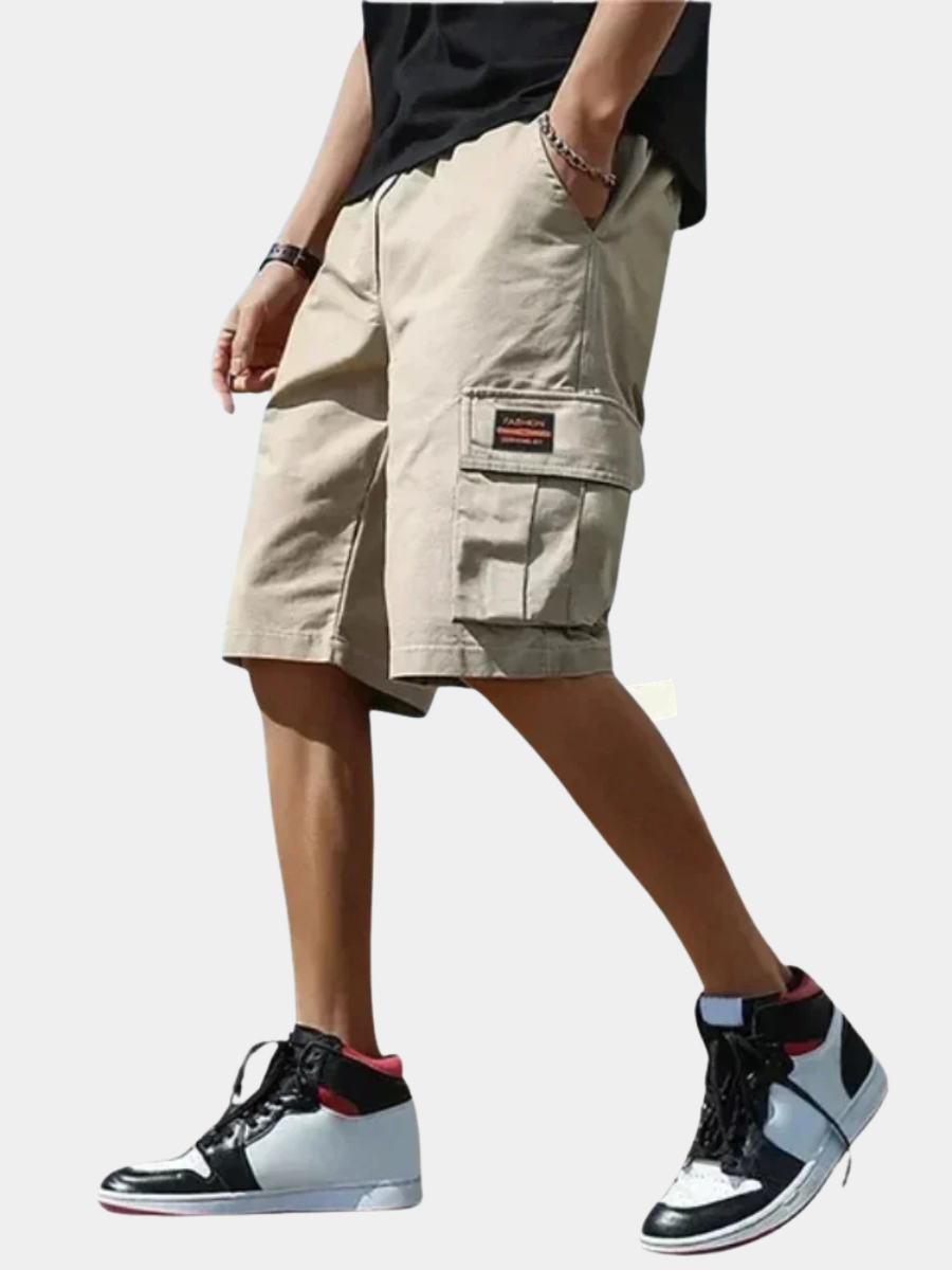 Beige men's cargo shorts with a drawstring waist, side utility pockets, and a loose, comfortable fit.