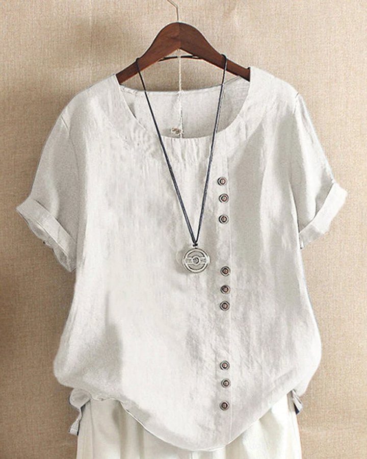 White linen tunic top with a relaxed fit, short rolled sleeves, and an asymmetrical button-front detail.