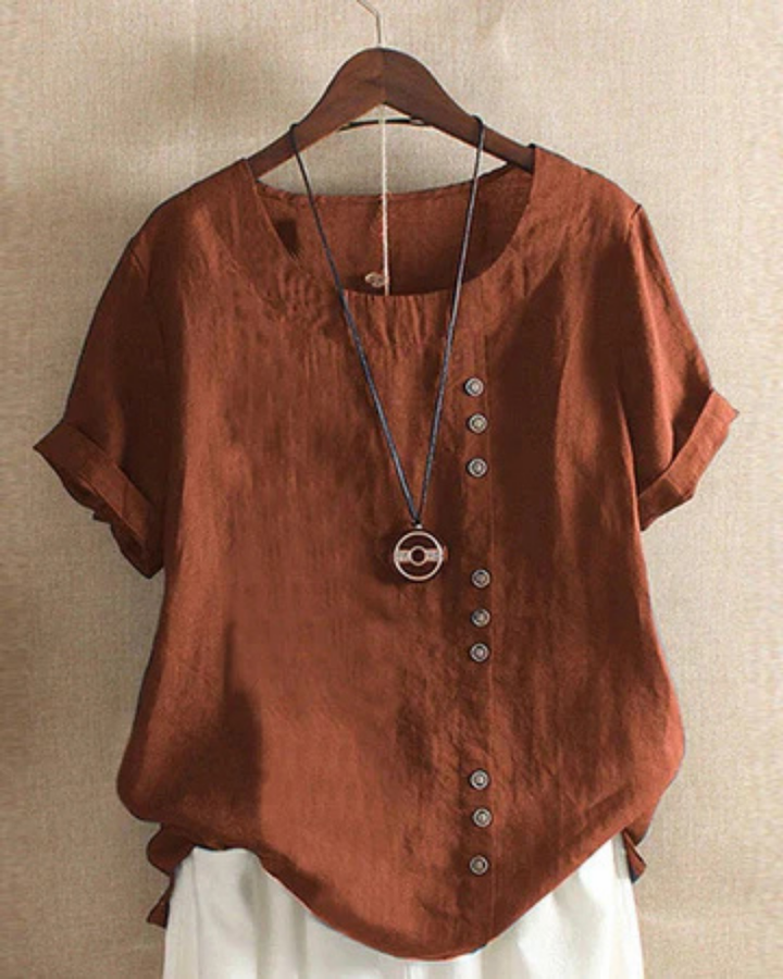 Rust-colored linen tunic with a relaxed fit, side button-front detail, and rolled short sleeves.