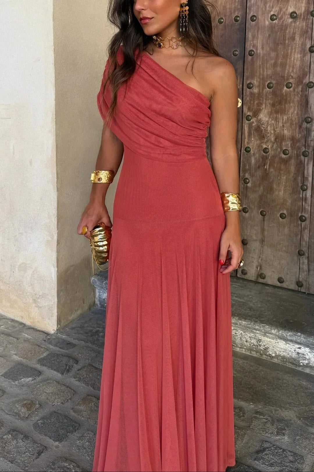 Nora women's one-shoulder pleated maxi dress in a rich coral hue, styled with gold jewelry.