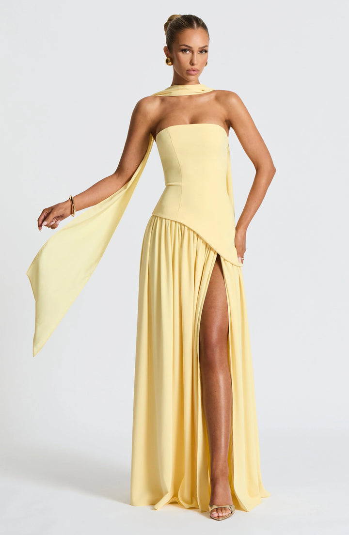 Black strapless corset maxi dress with a high slit, made from a sleek, flowing fabric.