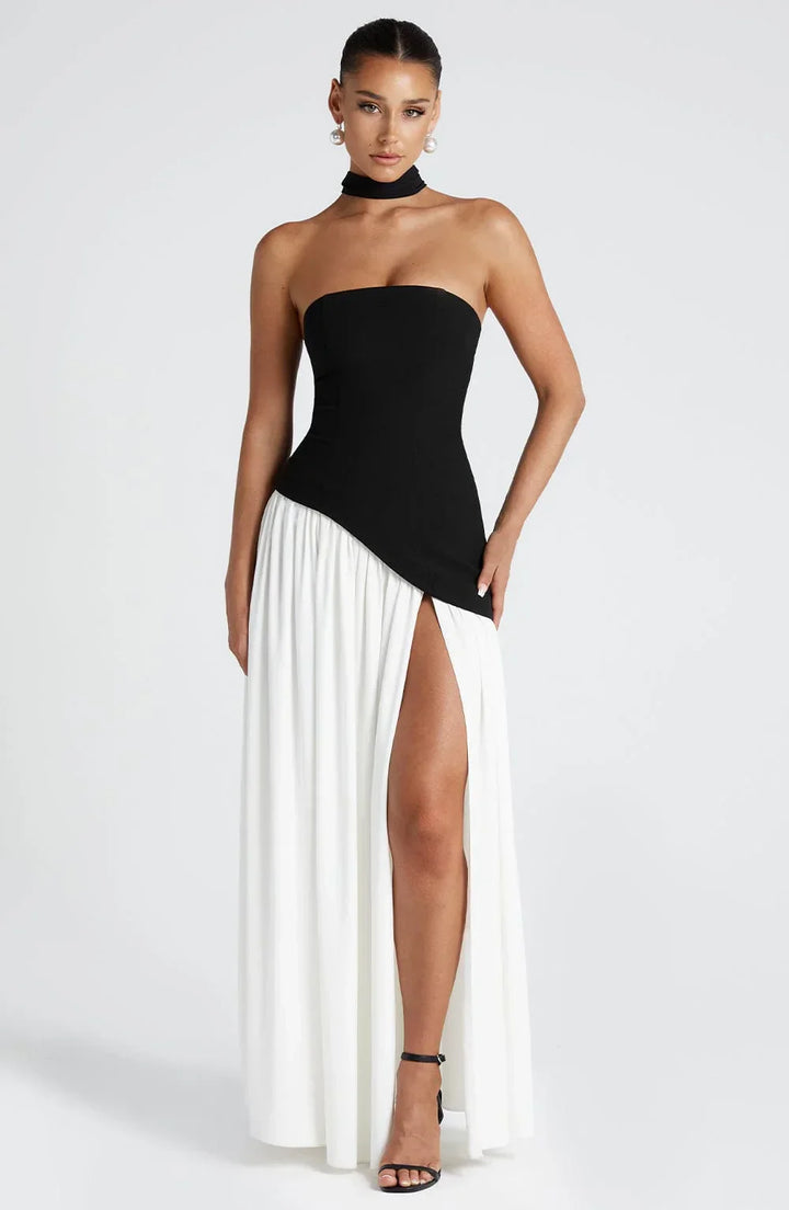 Black strapless corset maxi dress with a high slit, made from a sleek, form-fitting material.