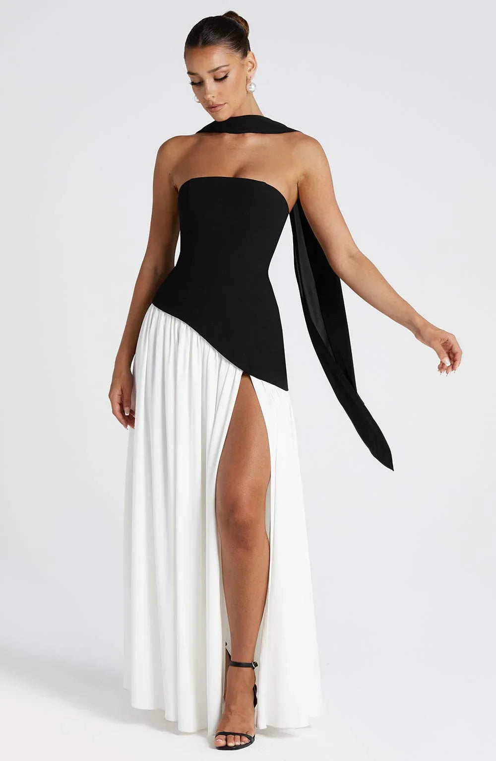 Black strapless corset maxi dress with a high slit, made from a sleek, flowing fabric.