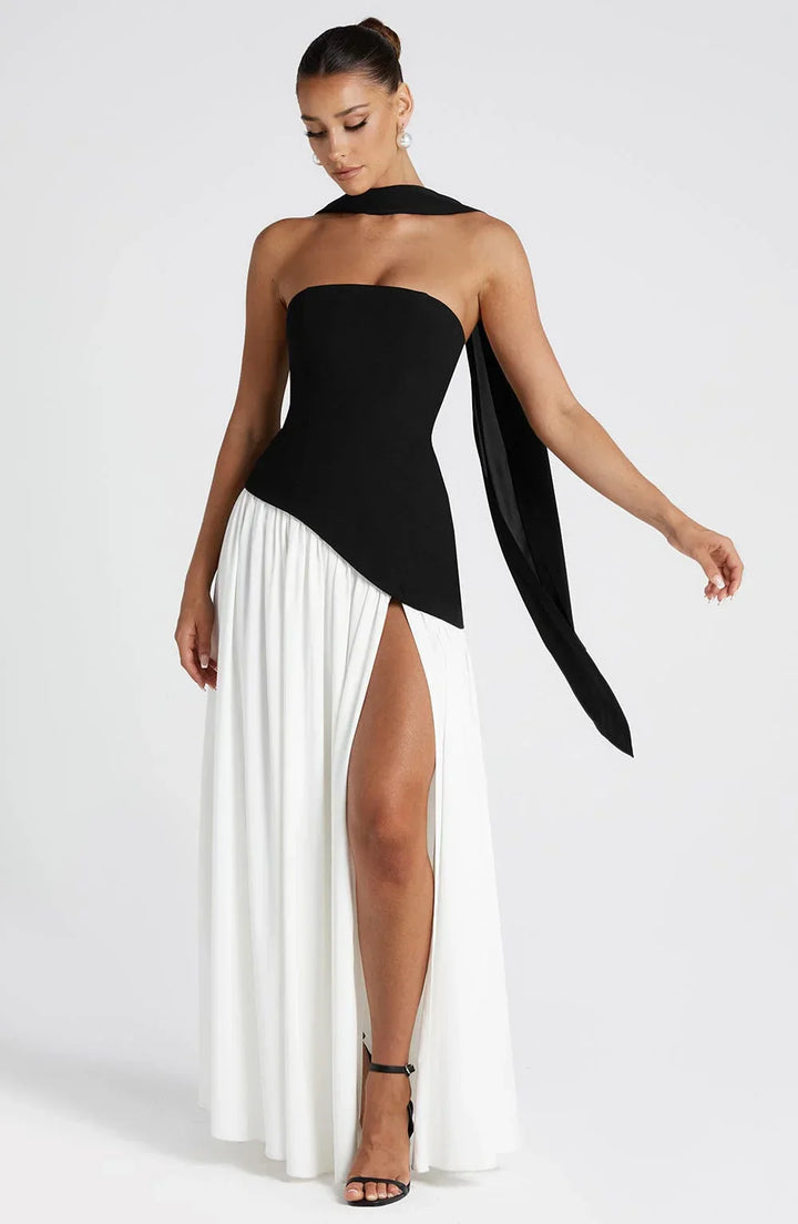 Black strapless corset maxi dress with a high slit, made from a sleek, flowing fabric.