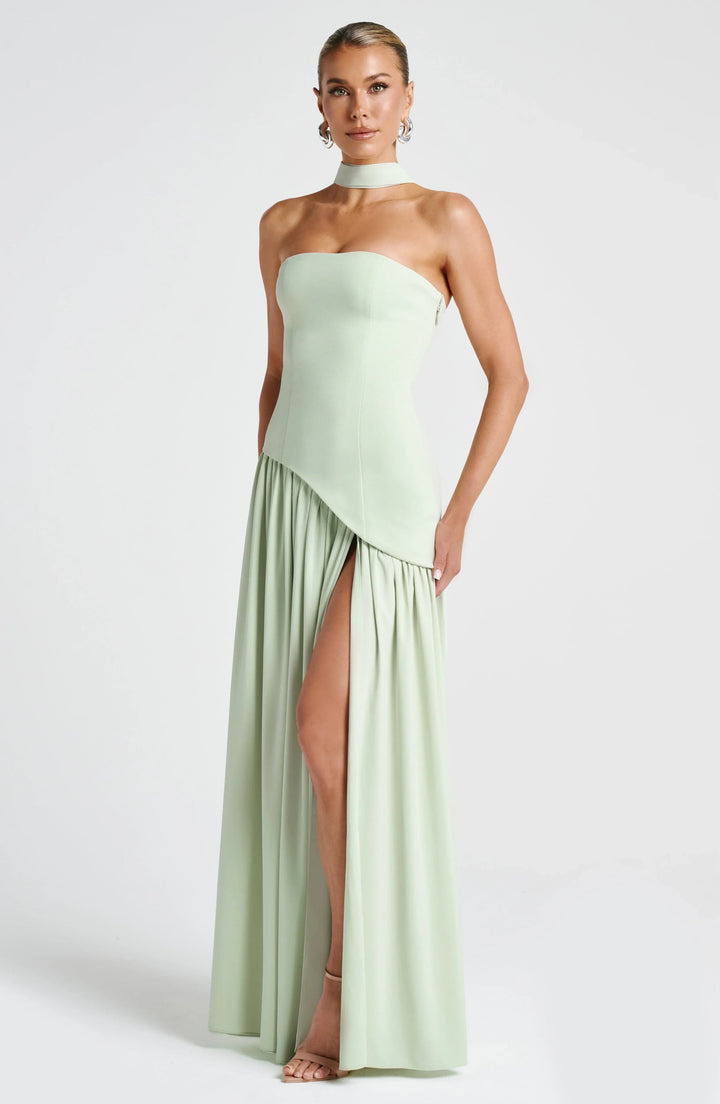 Black strapless corset maxi dress with a high slit, made from a sleek, flowing fabric.