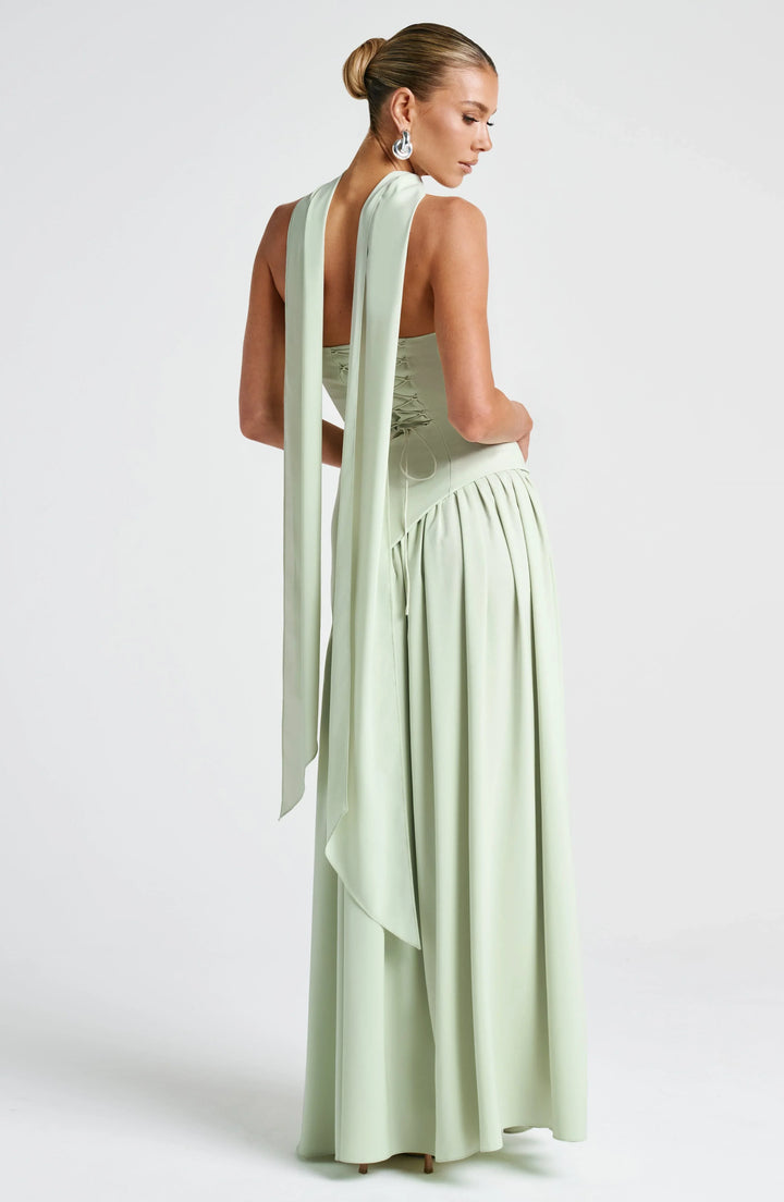 Black strapless corset maxi dress with a high slit, made from a sleek, form-fitting fabric.