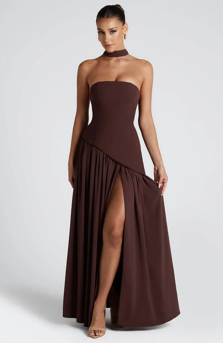 Black strapless corset maxi dress with a high slit, made from a sleek, form-fitting fabric.