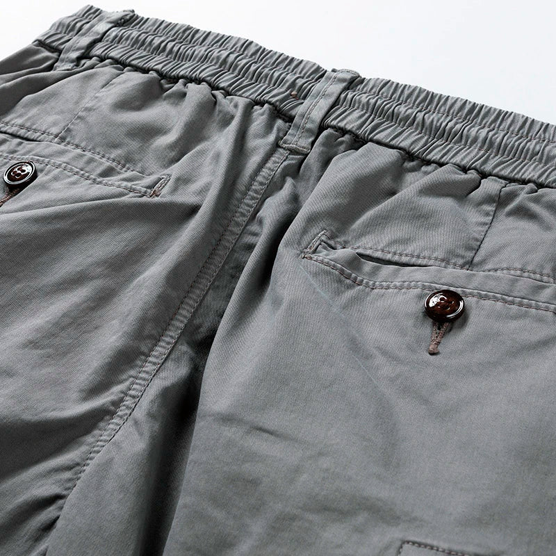 Close-up of gray men's drawstring cargo shorts with elastic waist and buttoned back pockets.