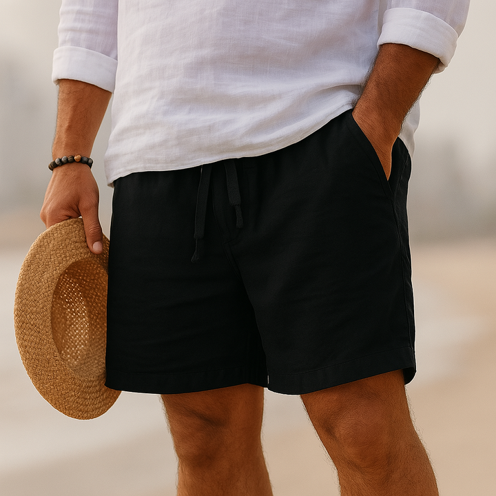 Men's black above-knee drawstring shorts with side pockets, paired with a white linen shirt.
