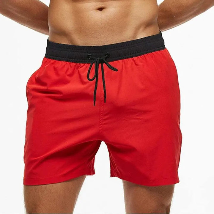 Men's red Reid swim shorts with a black elastic drawstring waistband.