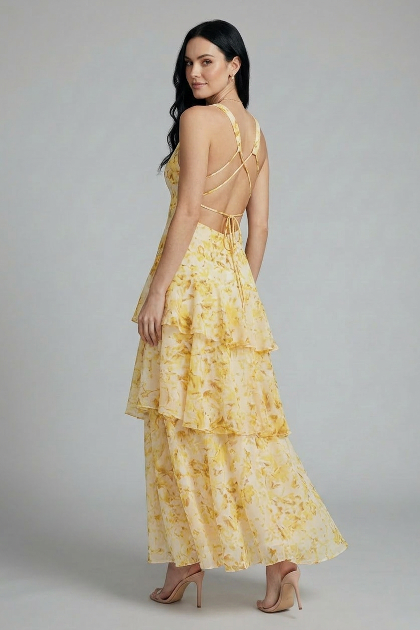 Woman in a yellow floral maxi dress with a deep V-neck, crisscross back, and layered ruffle skirt.