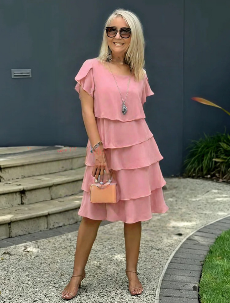 Sophia women's short sleeve layered midi dress in soft pink, styled with heels and a clutch.