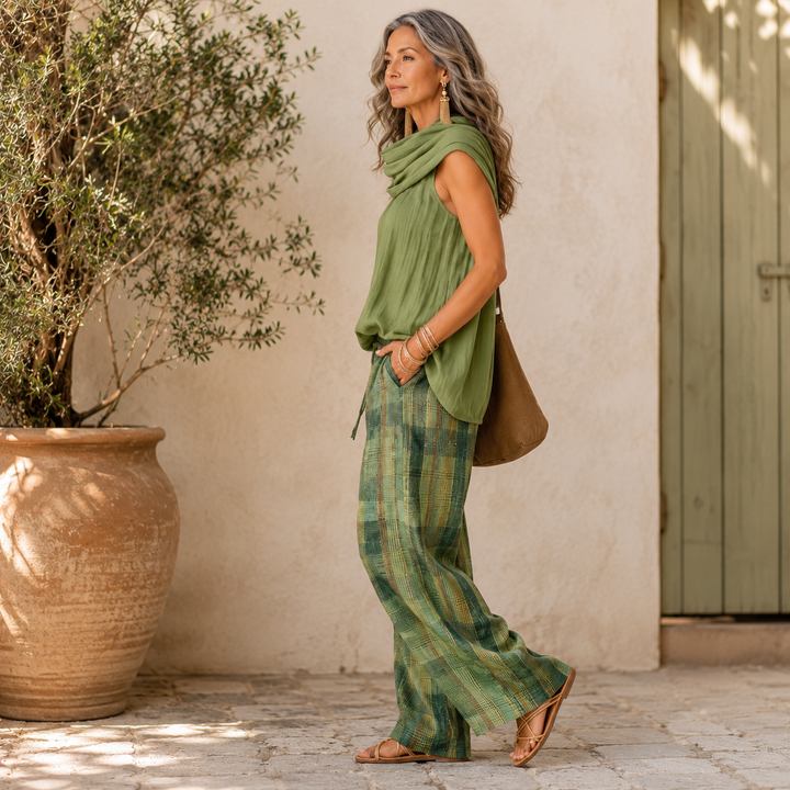 Woman in a green sleeveless blouse and matching plaid wide-leg pants with a cowl neck scarf.