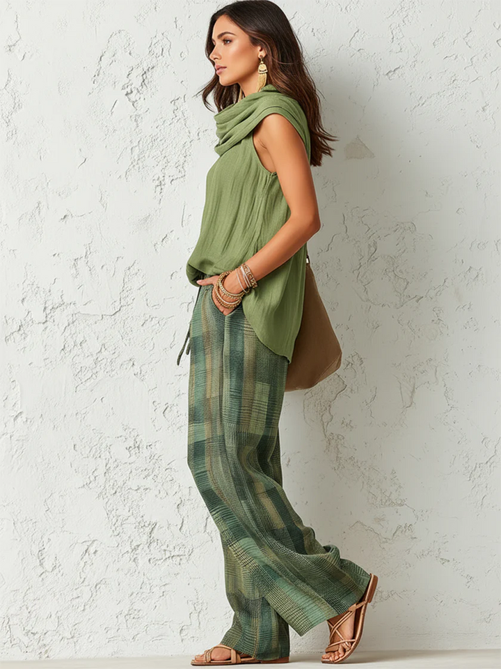 Woman in Stella green sleeveless blouse with matching scarf and plaid wide-leg pants.
