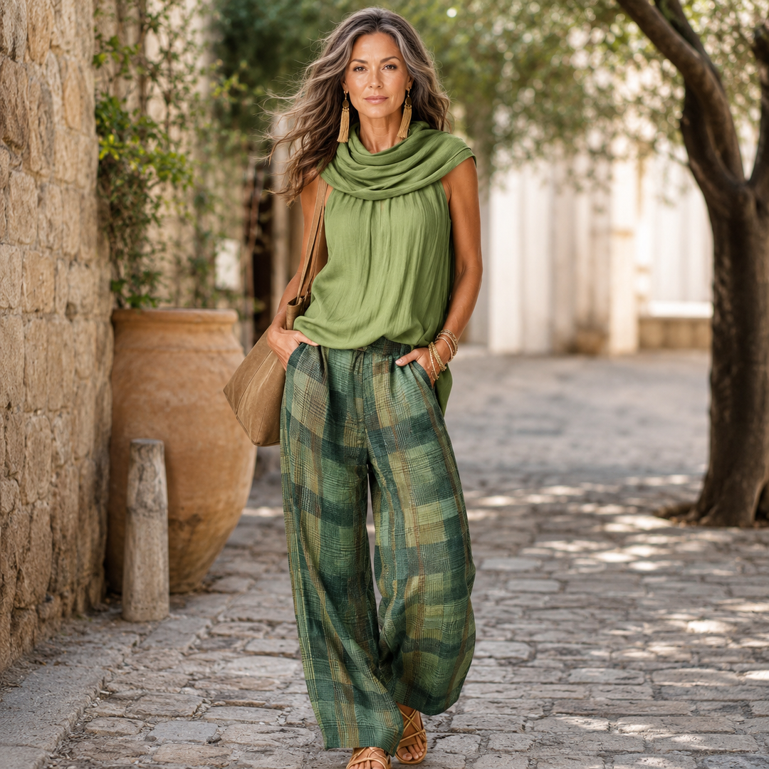 Woman in a green sleeveless blouse and matching plaid wide-leg pants walking outdoors.