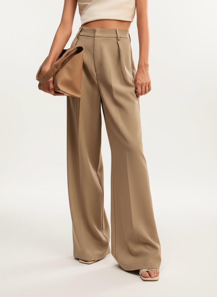 Stella women's high-waist wide-leg pants in a flowing tan fabric, styled with a cropped top and matching bag.