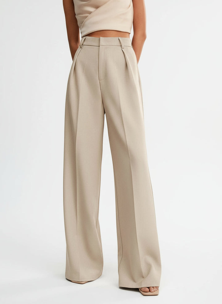 Stella women's high-waist wide-leg pants in a flowing beige fabric with tailored pleats.
