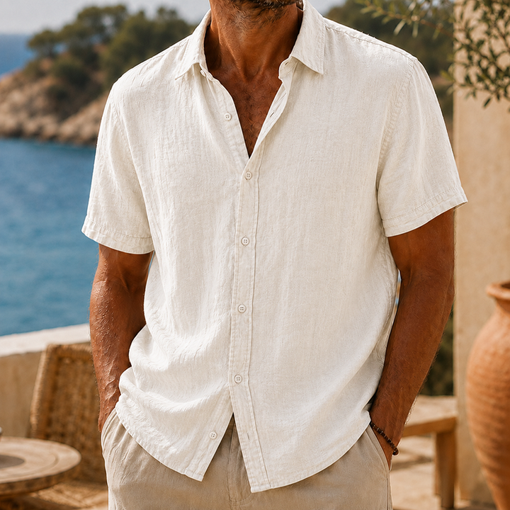 Men's Tyson natural linen short sleeve button shirt with collared neckline, worn with hands in pockets.