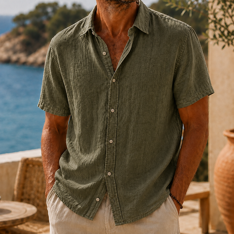 Men's olive green linen short sleeve button-up shirt with a collared neckline, worn casually outdoors.