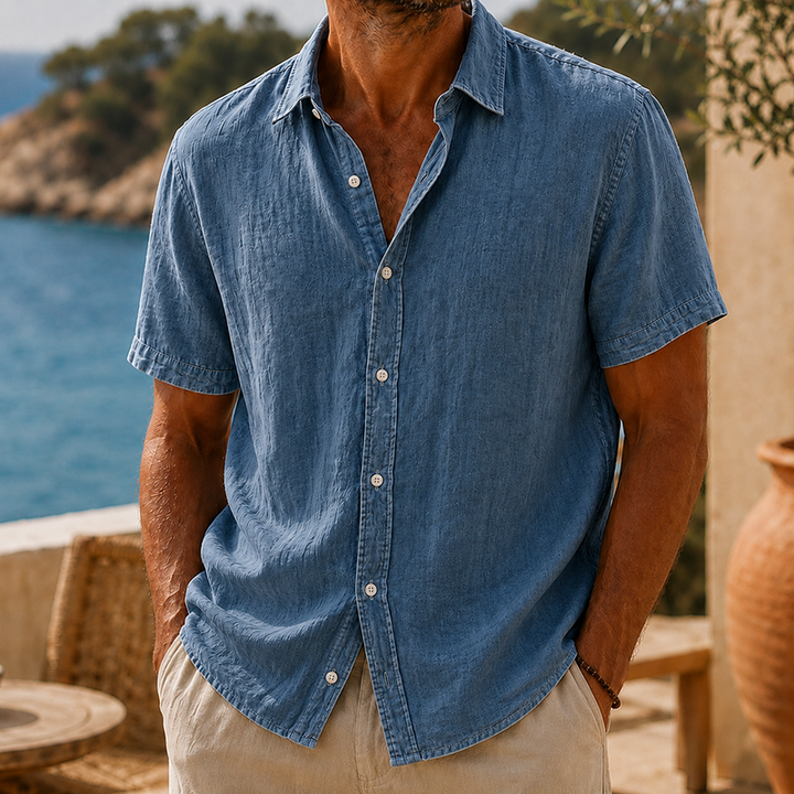 Men's Tyson blue linen short sleeve button shirt with a collared neckline, worn with tan pants.