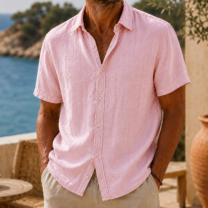 Men's pink linen short sleeve button shirt with a collared neckline, paired with khaki pants.