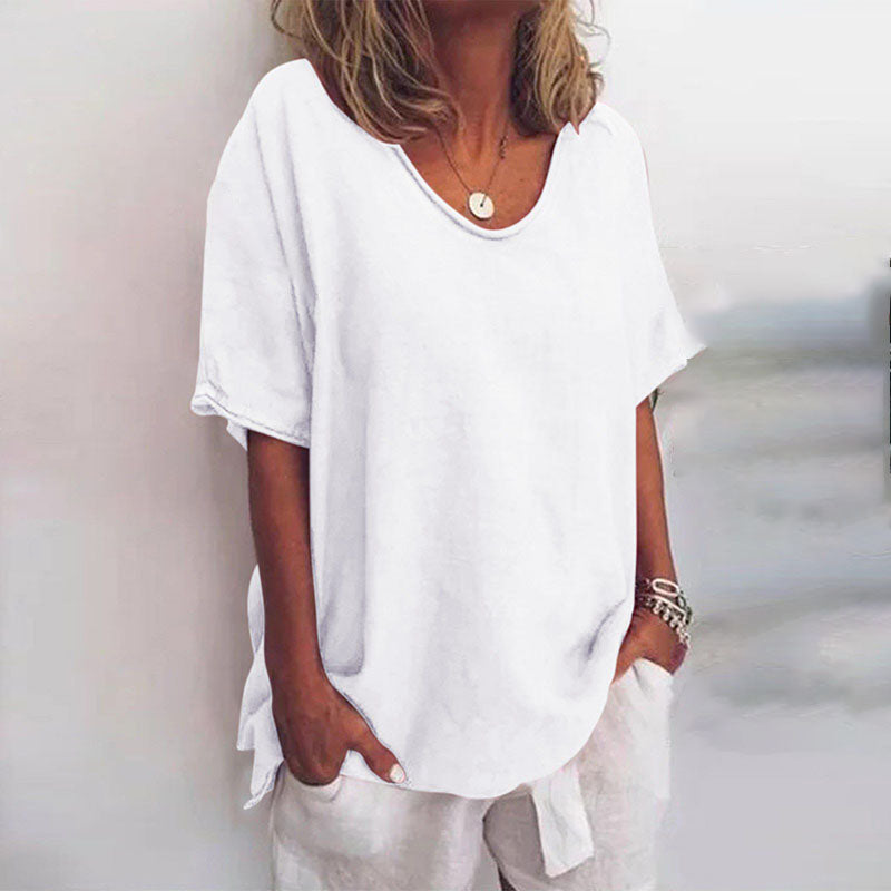 Woman wearing a white, loose-fitting V-neck blouse with short sleeves and a soft, draped silhouette.