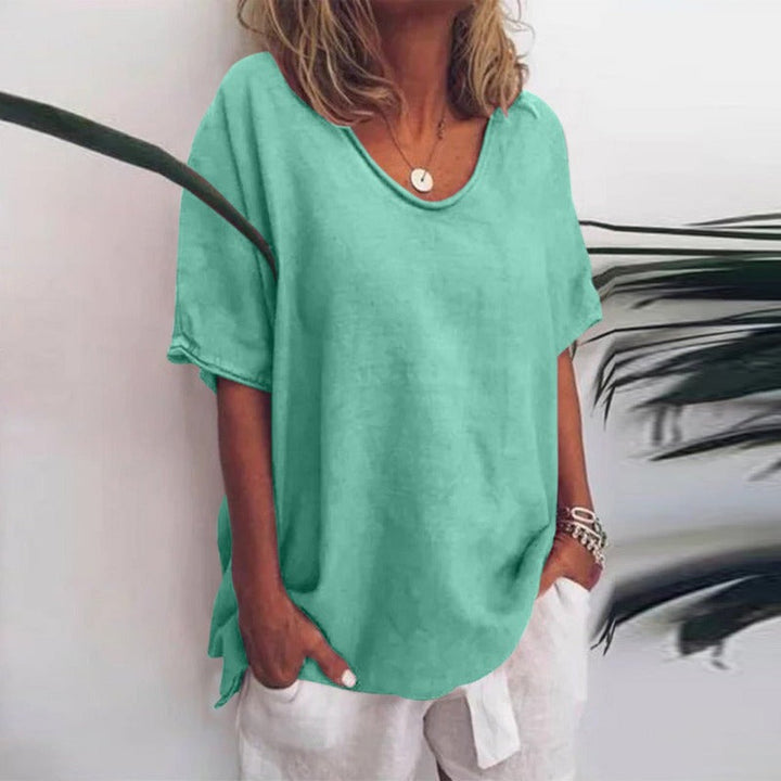 Woman wearing a soft, mint green V-neck flow blouse with short sleeves and a relaxed, draped fit.