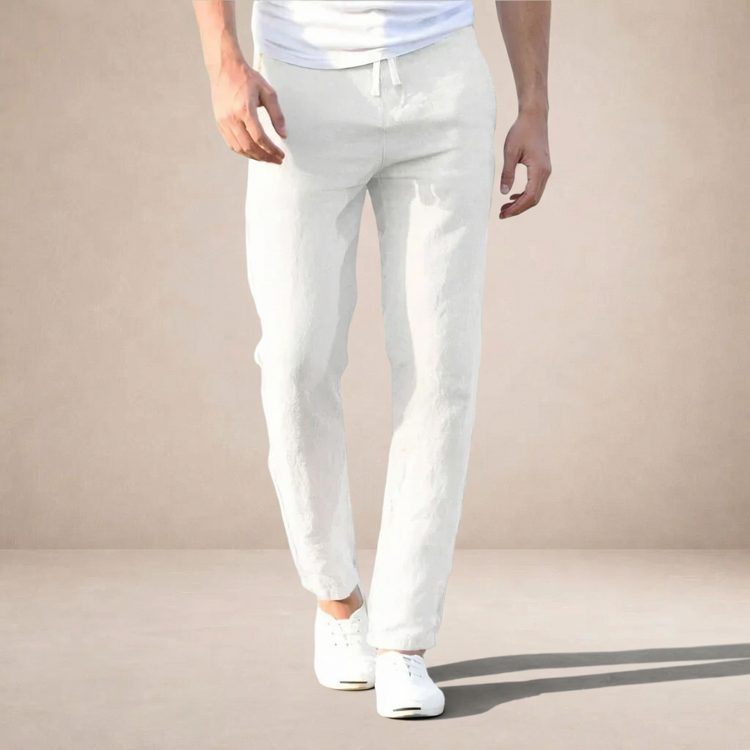 Men's white linen summer pants with a straight leg, drawstring waist, and side pockets, paired with white sneakers.