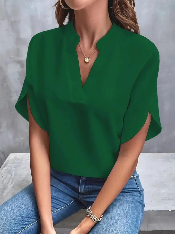 Willa women's emerald green V-neck blouse with flowy split sleeves, paired with jeans.