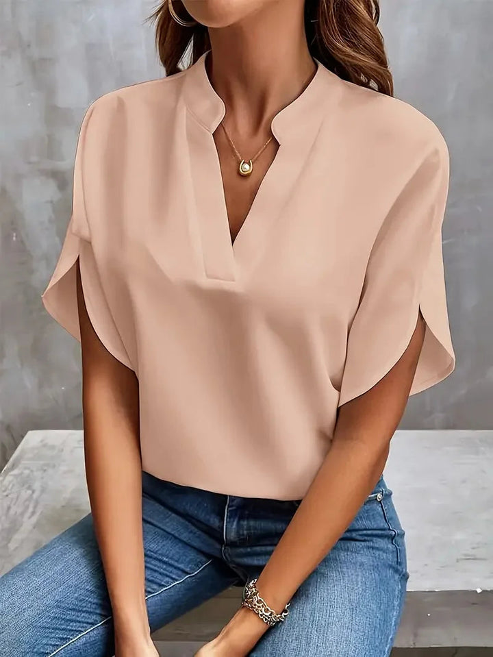 Willa women's blush V-neck blouse with flowy short sleeves, paired with jeans.
