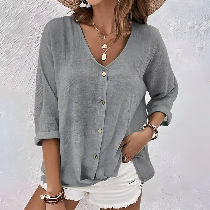 Women's white V-neck button-up blouse with long sleeves, made from a light, flowing fabric.