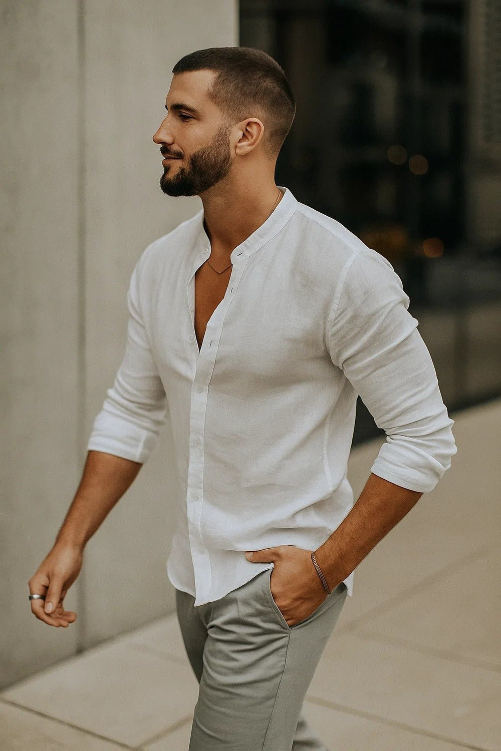 Men's white linen band collar button-up shirt with rolled sleeves and light gray pants.